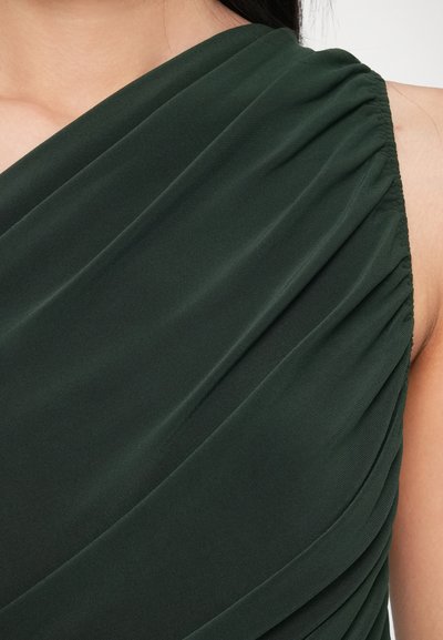 Tmavozelený šifónový materiál prehodený cez plece, s jemnými záhybmi a zhromaždenými detailmi na šve pre textúrovaný vzhľad.