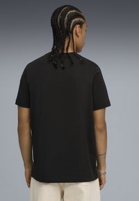 Sort bomulds T-shirt med korte ærmer og lige snit, set fra ryggen. Har et ensfarvet design og blød tekstur.