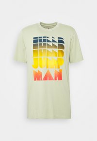 Camiseta de algodón verde claro con un diseño de texto en degradado en azul marino, amarillo y rojo. Mangas cortas y cuello redondo clásico.