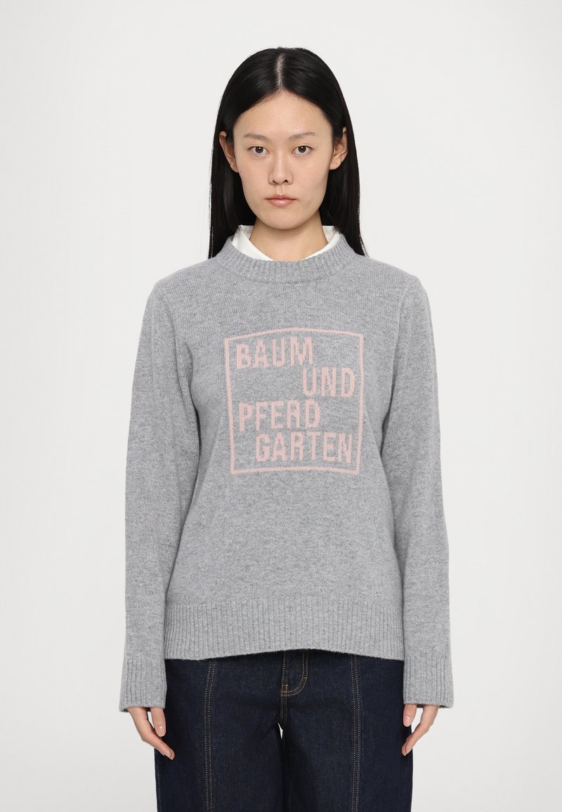 Maglione grigio, con polsini e orlo a coste, caratterizzato da una grafica quadrata rosa con testo "BAUM UND PFERDGARTEN" al centro, realizzato in materiale morbido.