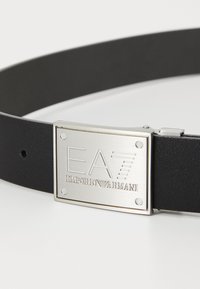 Čierny kožený opasok so striebornou kovovou sponou s vystúpeným textom "EA7 EMPORIO ARMANI" a obdĺžnikovým dizajnom, jemná textúra.