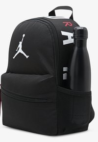 Μαύρο υφασμάτινο σακίδιο με λογότυ πο Jumpman σε λευκό, πλαϊνή θήκη από δίχτυ για μπουκάλι νερού και έντονες λευκές και κόκκινες γραφές.