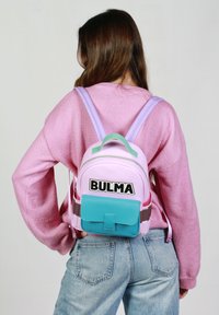 Sac à dos en rose et violet clair, doté d'une poche avant turquoise, d'un texte "BULMA" en noir et de bretelles réglables. Le tissu semble lisse avec une finition brillante.