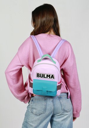 Mochila en rosa y morado claro, con un bolsillo frontal en color aguamarina, texto negro "BULMA" y correas ajustables. La tela parece suave con un acabado brillante.