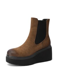 Stivaletto in suede marrone con pannello elastico nero ai lati, punta rotonda e suola platform nera chunky. Presenta una texture liscia e un design elegante.