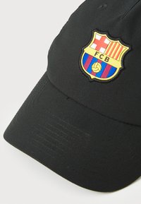 Black baseball cap featuring an embroidered FC Barcelona crest, with red and yellow stripes, blue and maroon vertical bands, and a textured surface.
