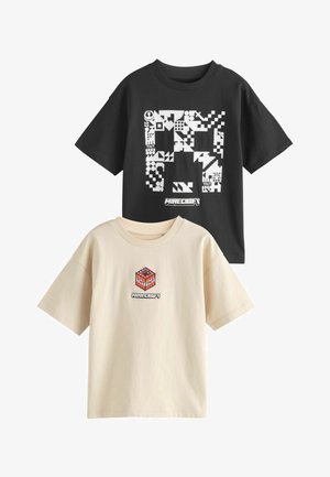 Fekete és bézs színű pólók Minecraft mintákkal. A fekete pólón fehér pixeles mintázat látható; a bézsen piros és fekete TNT kocka grafika található.
