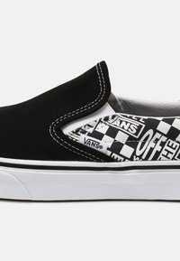Chaussure Vans slip-on noir et blanc avec motif damier et logo "Off The Wall", semelle blanche et étiquette de marque visible.