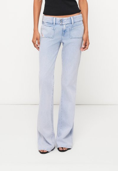 Jean flare bleu délavé avec taille mi-haute, fermeture à double bouton et deux poches arrière. Tissu texturé avec couture visible.