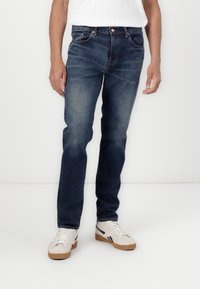 Jeans de denim azul oscuro con corte recto, ligero desvanecido, diseño clásico de cinco bolsillos y detalles de costura en las costuras.