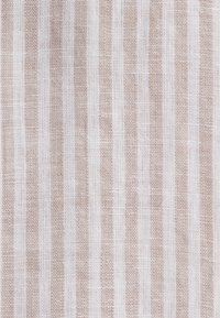 Tissu tissé rayé vertical beige et blanc avec un aspect texturé rappelant la toile de jute et des motifs de fils visibles.