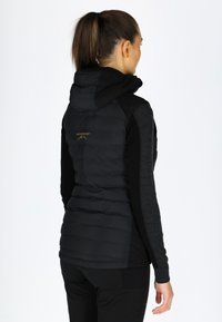 Gilet imbottito nero con cappuccio, caratterizzato da texture trapuntata, pannelli laterali grigi a contrasto e dettaglio in oro sul retro.