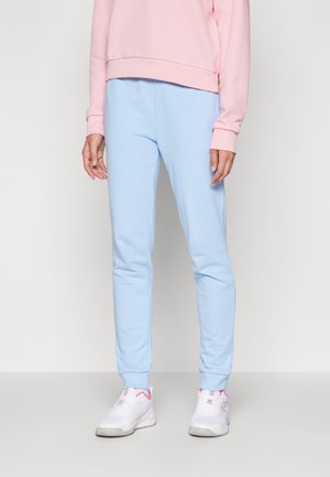 Pantalones de chándal azul claros en tejido suave con un ajuste cónico. Combinados con una sudadera rosa y zapatillas blancas con acentos rosas.