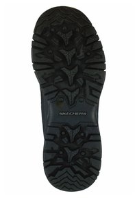 Suola di scarpa in gomma nera con scanalature profonde e pattern testurizzato, con il logo "SKECHERS". Adatta per garantire aderenza su diverse superfici.