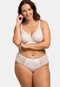 Ensemble de lingerie en dentelle blanche comprenant un soutien-gorge et une culotte, ornés de motifs géométriques, de bords festonnés et d'un bouton central. Tissu doux et texturé.