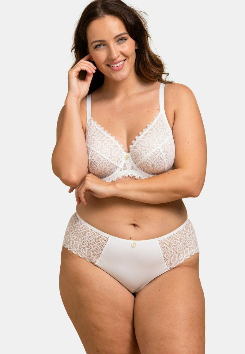 Ensemble de lingerie en dentelle blanche comprenant un soutien-gorge et une culotte, ornés de motifs géométriques, de bords festonnés et d'un bouton central. Tissu doux et texturé.