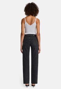 Jeans neri a gamba dritta con vita alta, cinque tasche e cuciture a contrasto, abbinati a un top in maglia a costine grigio chiaro.