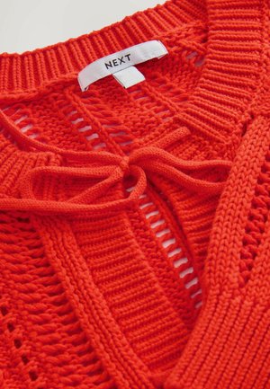 Rød strikket sweater med åbent væv, prydet med en bundet halsudskæring. Etiket med teksten "NEXT." Struktureret stof med ribbede kanter og detaljeret syning.