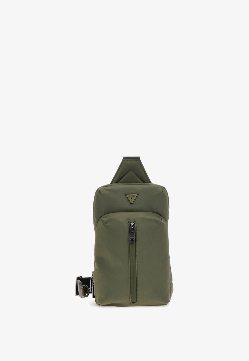 Mochila verde oliva en tejido duradero, con un logotipo triangular, bolsillo frontal con cremallera y correa ajustable con herrajes metálicos.