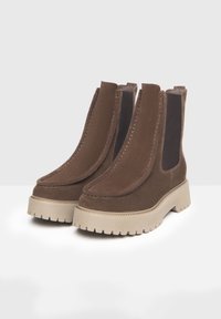 Bottines en suede marron avec panneaux élastiques sur les côtés, bout rond et épaisse semelle plateforme beige dotée d'un relief pour une meilleure adhérence.