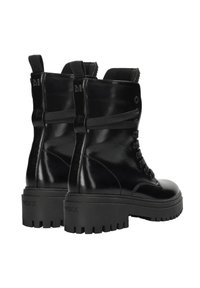 Zwarte glanzende combatlaarzen, van leer, tot halverwege de kuit, met een rubberen zool met diepe noppen, veterbinding aan de voorkant en trekriemen aan de achterkant.