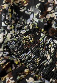 Auduma ar ziedu rakstu tumšās toņos ar zaļām, dzeltenām un brūnām niansēm. Raksturots ar teksturētu savērpuma detaļu un vieglu materiālu.