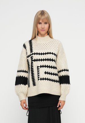 Knit sweater in cream with black geometric patterns, featuring a high neck, oversized sleeves, and textured finishes in varying knit styles.