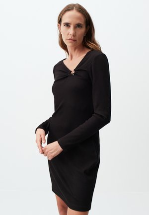 Black ribbed dress with long sleeves, scoop neckline, and a gathered feature secured by a small accent. Smooth texture and fitted shape.