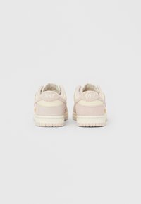 Pár světle růžových a krémových tenisek Nike zobrazených zezadu na jednobarevném bílém pozadí.