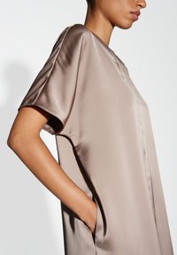 Tailliertes Satin-Kleid in Taupe mit kurzen Ärmeln, seitlichen Taschen und minimalistischem Design mit dezenten Nähten an der Vorderseite.