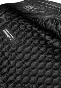 Interieur van een zwarte leren jas met een gewatteerde voering, voorzien van een hexagonaal patroon en een label met de tekst "pomboogie" en maat "L."