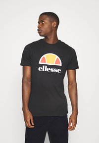 Camiseta negra con cuello redondo, que presenta un logotipo curvado colorido con acentos en amarillo, naranja y blanco. Hecha de una tela suave y transpirable.