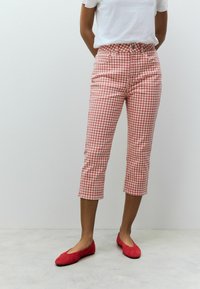 Rode en witte geruite cropped broek met een getailleerde taille, vijf zakken en een rechte pijp, gecombineerd met rode platte schoenen.