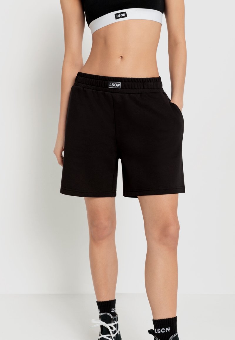 Zwarte katoenen shorts met een elastische tailleband, voorzien van een logo-label, zijzakken en een relaxte pasvorm, gecombineerd met een zwart-witte crop top.