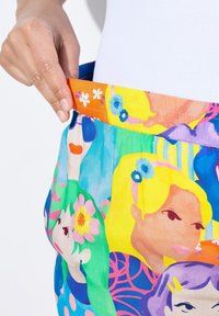 Barevné, vzorované dámské šortky s elastickým pasem, zdobené květinovými a kreslenými motivy v živých odstínech modré, růžové a žluté.