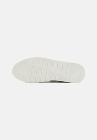 White sneaker sole with a textured rubber surface, featuring horizontal and vertical grooves for traction. Markings include brand logo and size.