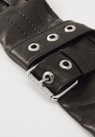 Zwarte leren riem met zilverkleurige hardware, voorzien van drukknoopdetails en decoratieve stiksels. Glad textuur en een verstelbaar ontwerp.