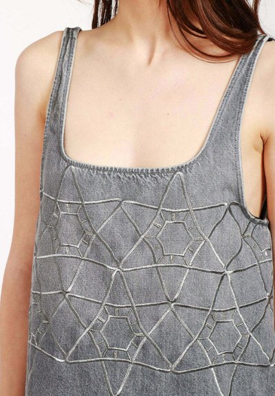 Top in denim grigio con spalline larghe, caratterizzato da intricati ricami bianchi a forma di stella e esagono. Scollo quadrato e tessuto testurizzato.