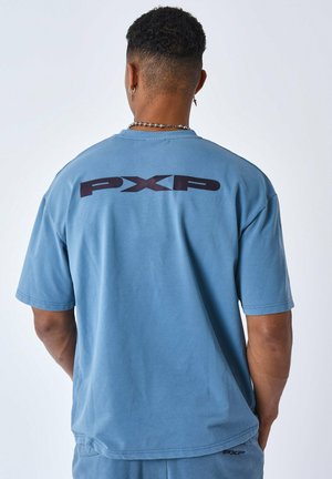 Losse blauwe katoenen t-shirt met een grote donkere tekst "PXP" op de achterkant. Ronde hals en korte mouwen, gladde textuur.