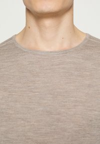 Hellbraunes, geripptes T-Shirt mit rundem Ausschnitt und dezenter Textur für ein weiches Aussehen. Das Material wirkt leicht und atmungsaktiv.