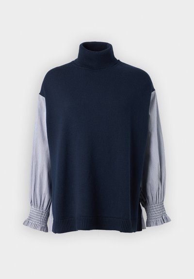 Navy knitted sweater with high collar, featuring striped fabric sleeves and ruffled cuffs. Soft texture, loose fit, and seam detailing.
