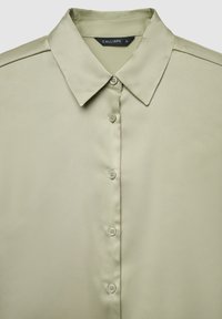 Hellolivgrüne Satinbluse mit spitzem Kragen, Knopfleiste vorne und sichtbarem Markenlabel "Calliope" in Größe S.