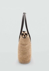 Geantă împletită, cu o formă rotundă, din materiale naturale de paie, cu mânere din piele închisă la culoare și o suprafață texturată. Design cu deschidere în partea de sus.