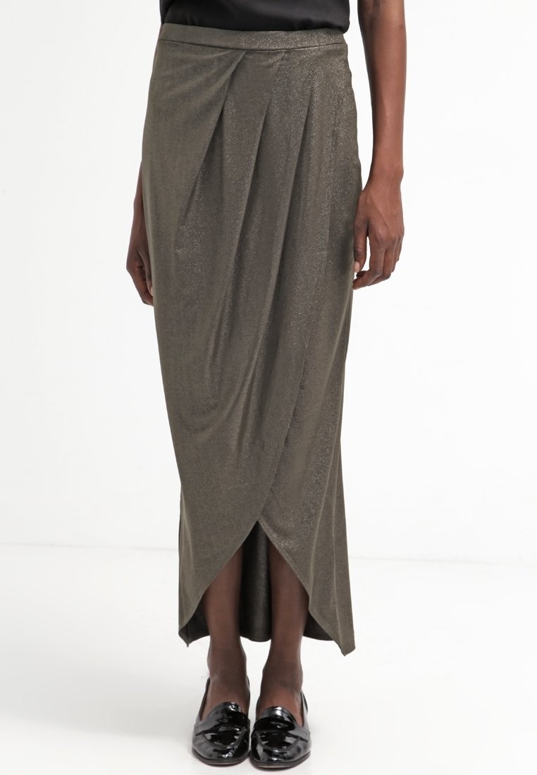 Lång, olivgrön kjol med metallisk lyster, med en draperad design och en omslags siluett, i kombination med svarta, blanka loafers.
