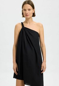 Vestido negro hecho de tela ligera, con una sola tirante trenzado en el hombro y un diseño drapeado, que presenta un dobladillo asimétrico.