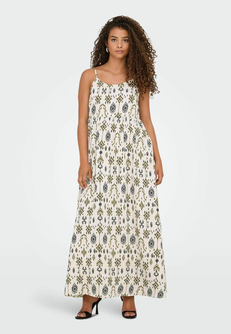 Maxi-jurk met dunne bandjes, beige stof, groene en grijze geometrische patronen, vloeiende silhouet en een losse pasvorm.