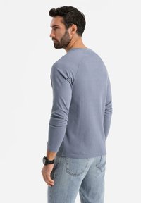Langsleeve blauwe geribbelde shirt met een ronde hals, in combinatie met lichtblauwe denim jeans, met een casual pasvorm en een zachte textuur.