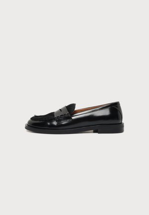 Mocassin en cuir noir avec un petit talon et un détail en fourrure noire sur le dessus, montré de côté extérieur sur fond blanc.