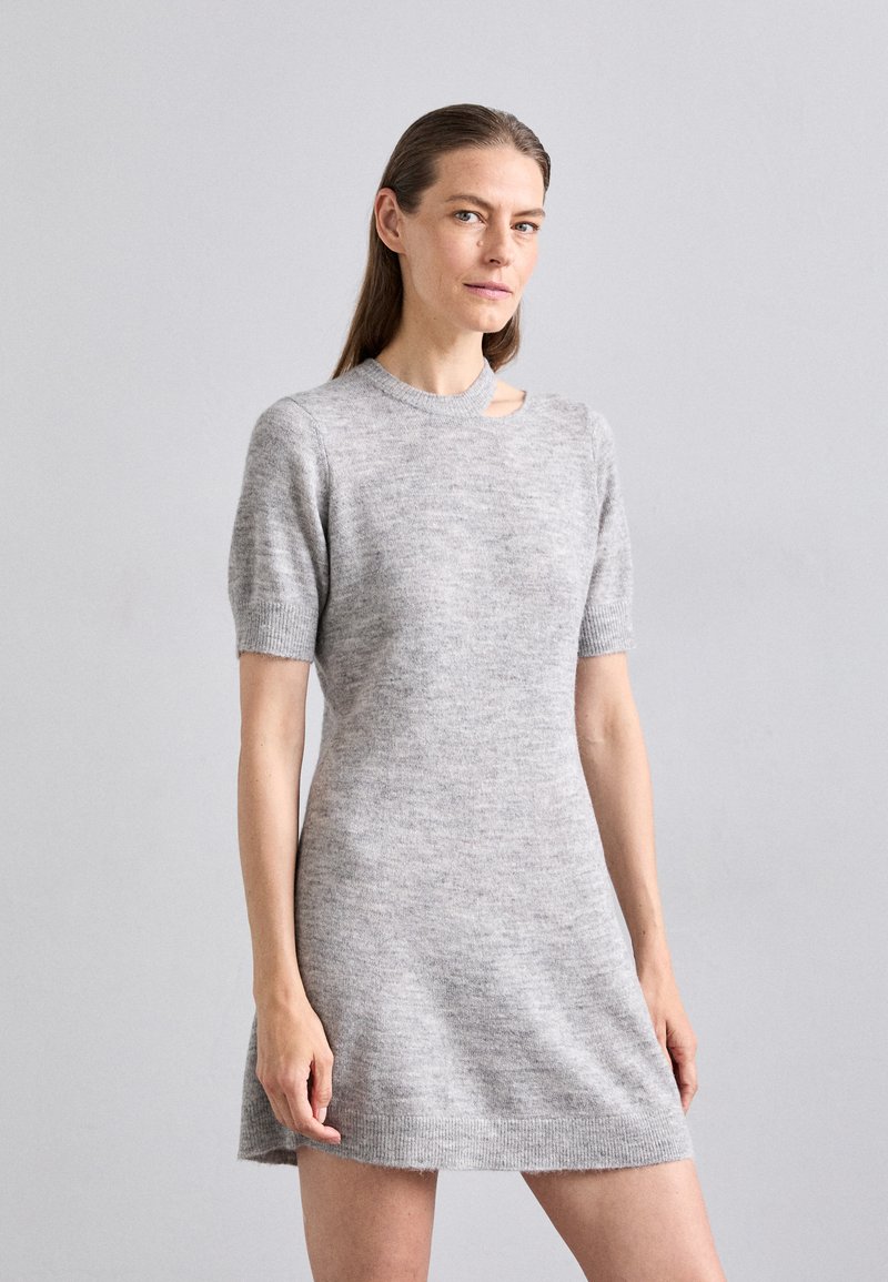 Robe tricotée gris clair avec des manches courtes, présentant un col rond et une découpe sur l'épaule. Texture douce et coupe décontractée.