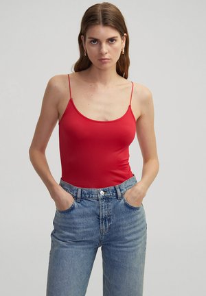 Bodysuit rojo sin mangas con tirantes finos, textura suave, combinado con pantalones vaqueros de mezclilla azul claro de cintura alta con bolsillos frontales.